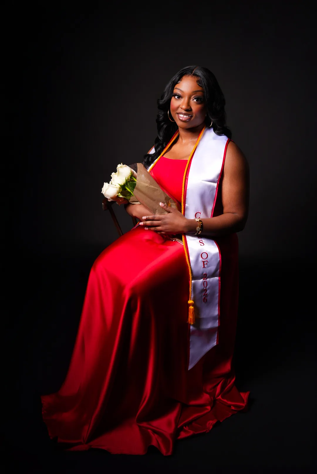 Graduate in a red gown against a black backdrop